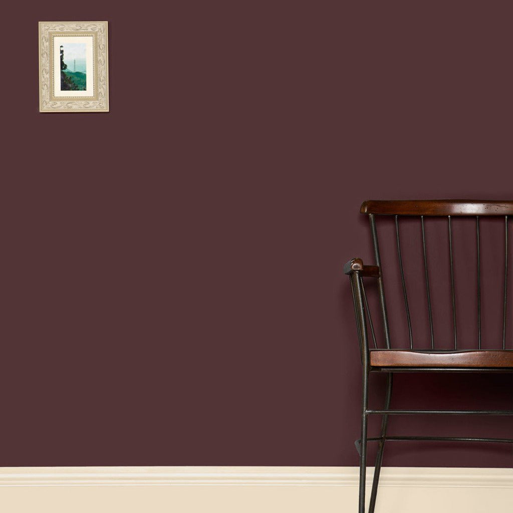 Wall painted Farrow & Ball Brinjal No.222 with a wooden chair in front and a small painting on the wall.